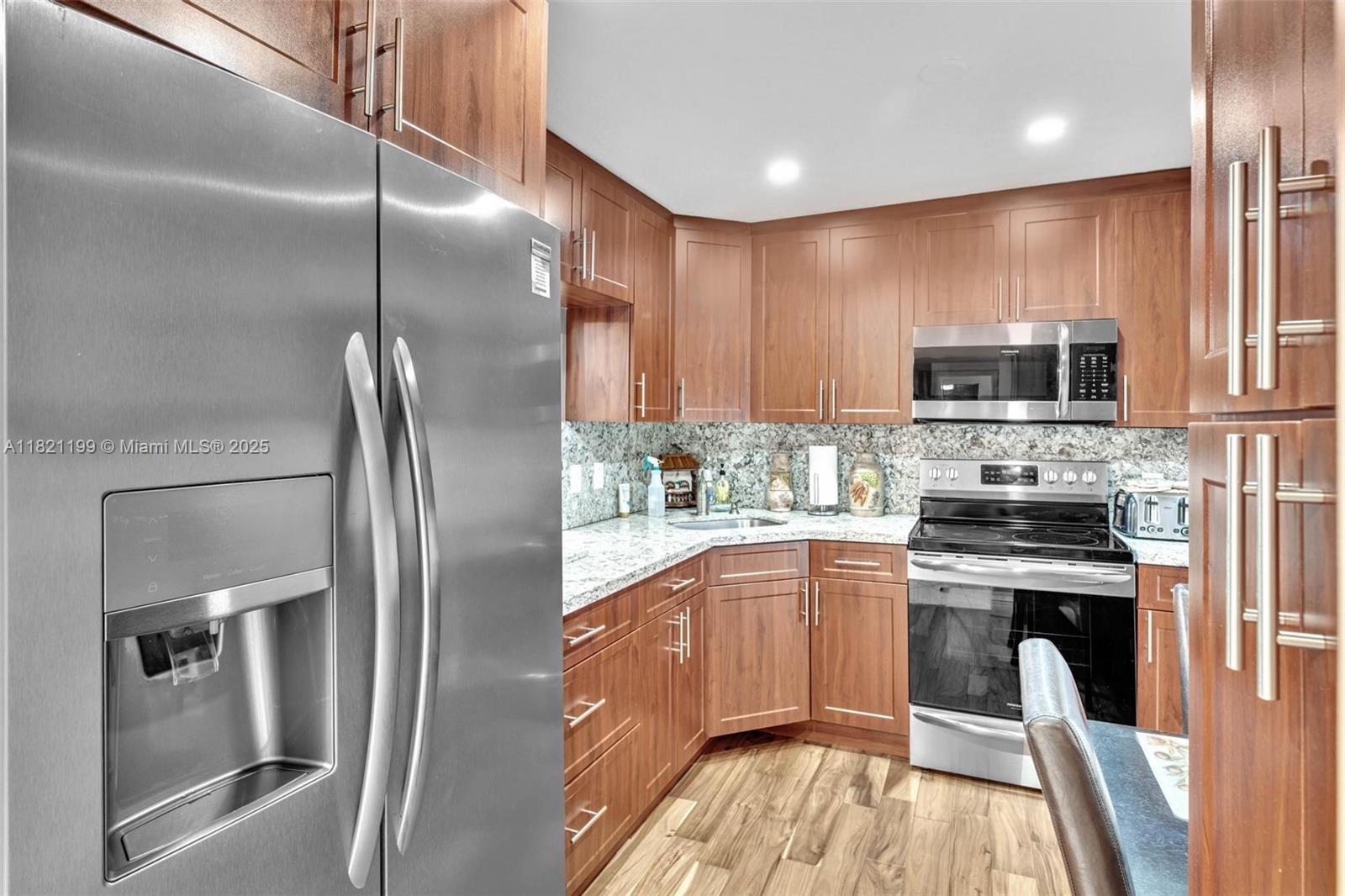 A kitchen features stainless steel appliances, wood cabinets, and granite countertops — 1865 S Ocean Dr # 5J, Hallandale Beach FL 33009, HALLANDALE BEACH, FL