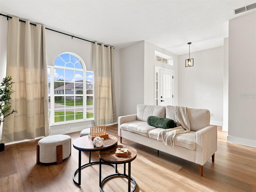 A living room features a beige sofa, nested coffee tables, and a large arched window — 2104 MALLARD CREEK CIRCLE, KISSIMMEE, FL
