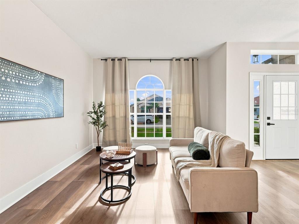 A living room features light wood floors, a beige sofa, and a large arched window — 2104 MALLARD CREEK CIRCLE, KISSIMMEE, FL