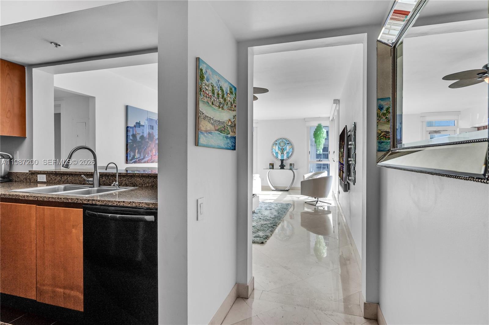 A kitchen with dark cabinets and granite countertops opens into a bright, tiled living area — 1500 Ocean Dr # 907, Miami Beach FL 33139, MIAMI BEACH, FL