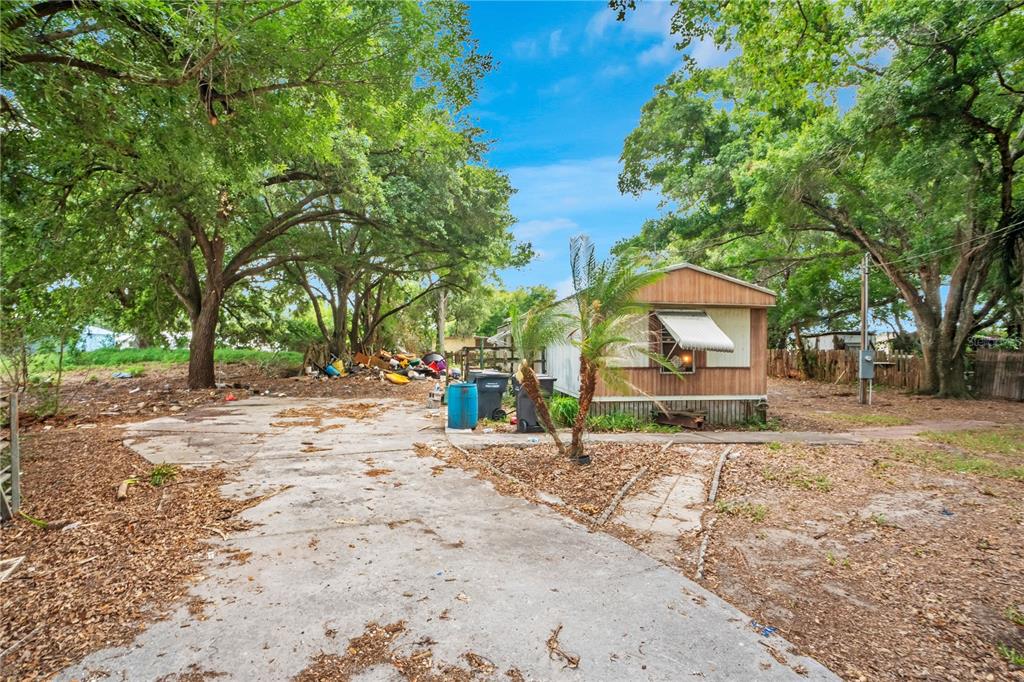 A mobile home sits on a lot with a concrete driveway and large shade trees — 124 6TH WAHNETA STREET W, WINTER HAVEN, FL