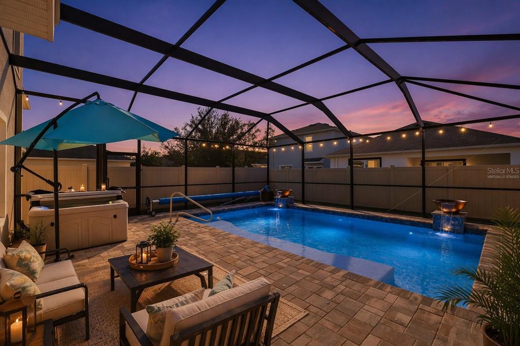 A screened-in patio features a swimming pool with water features, a hot tub, and furniture — 32756 ANSLEY BLOOM LANE, WESLEY CHAPEL, FL