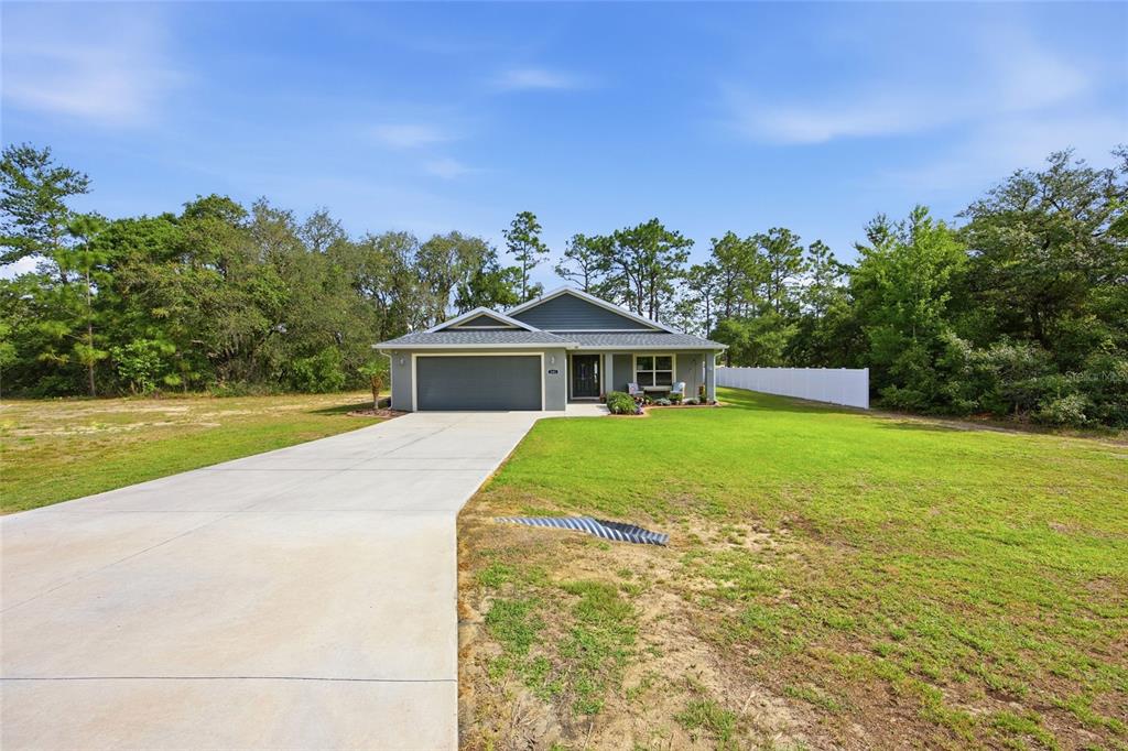A single-story house with a gray exterior, two-car garage, and a concrete driveway — 141 FISHER WAY, OCKLAWAHA, FL