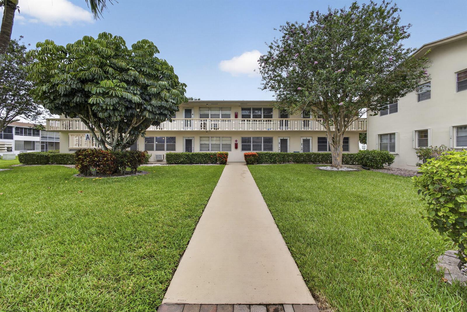 A two-story apartment building with a central walkway, green lawn, and mature trees — 5 Northampton A # 5, West Palm Beach FL 33417, WEST PALM BEACH, FL