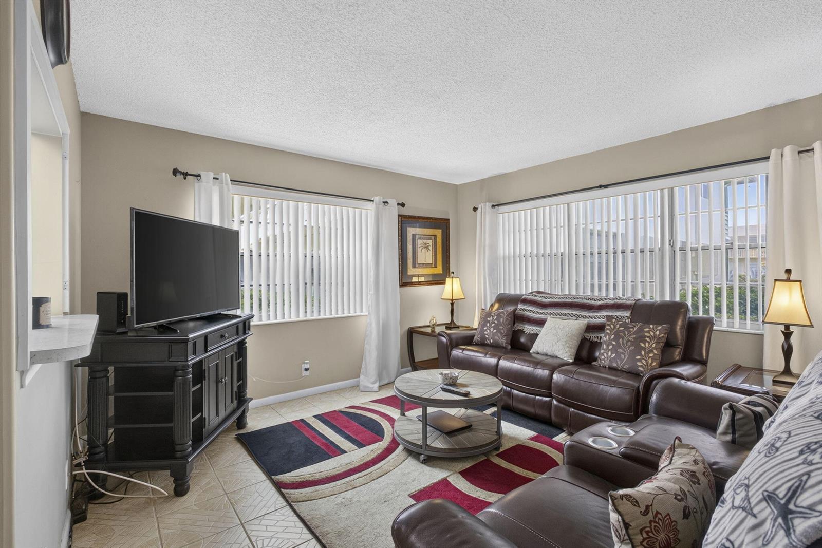 A living room features brown leather furniture, a patterned area rug, and two large windows — 5 Northampton A # 5, West Palm Beach FL 33417, WEST PALM BEACH, FL