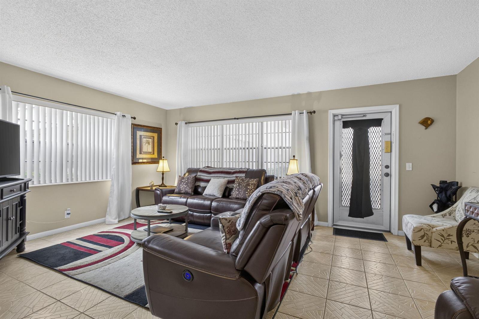 A living room features brown leather furniture, a patterned area rug, and tile flooring — 5 Northampton A # 5, West Palm Beach FL 33417, WEST PALM BEACH, FL