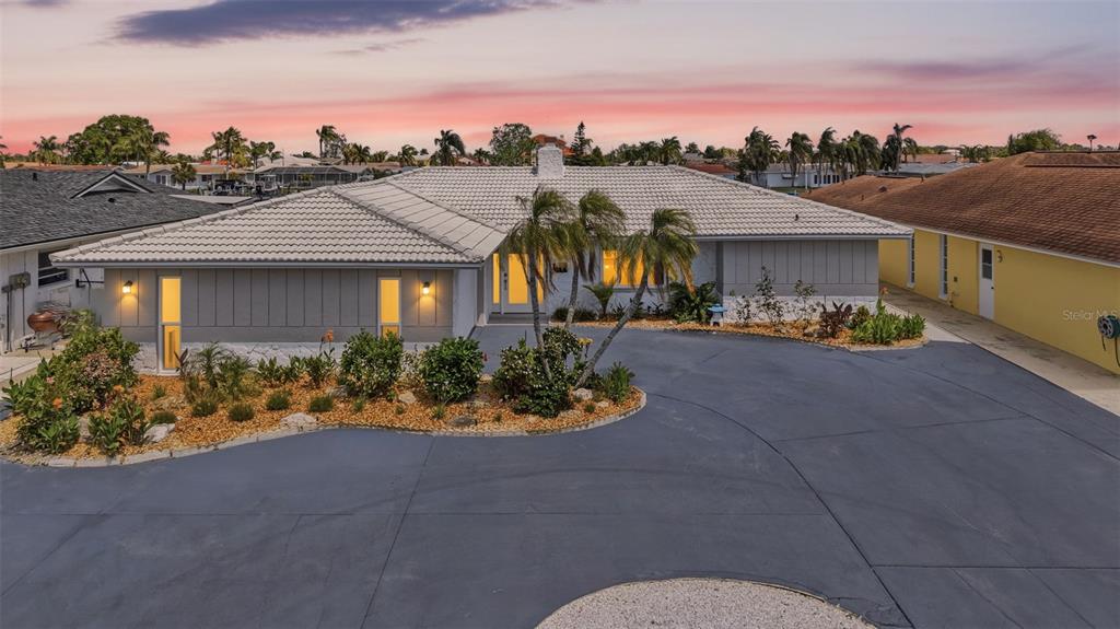 A single-story house with a light-colored tile roof and a large, paved circular driveway — 5040 GALLEON COURT, NEW PORT RICHEY, FL