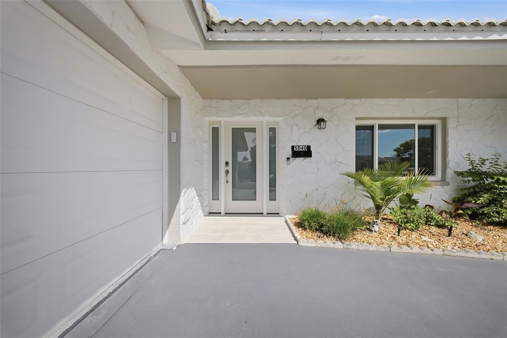 The exterior of a house features a white stone facade, a garage, and a front entrance — 5040 GALLEON COURT, NEW PORT RICHEY, FL