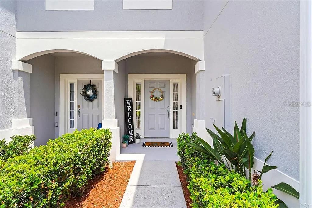 A concrete walkway leads to two light gray front doors under a covered porch — 1115 ROCK HARBOR AVENUE, ORLANDO, FL