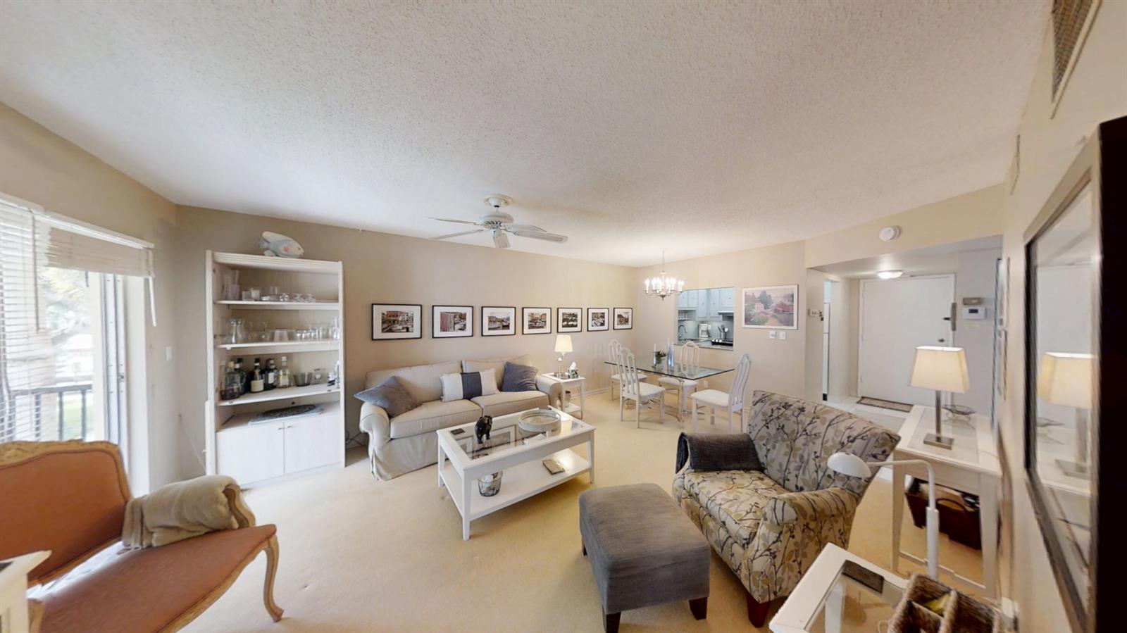 A living and dining room features beige carpet, neutral walls, and a glass-topped dining table — 259 S Cypress Road # 533, Pompano Beach FL 33060, POMPANO BEACH, FL