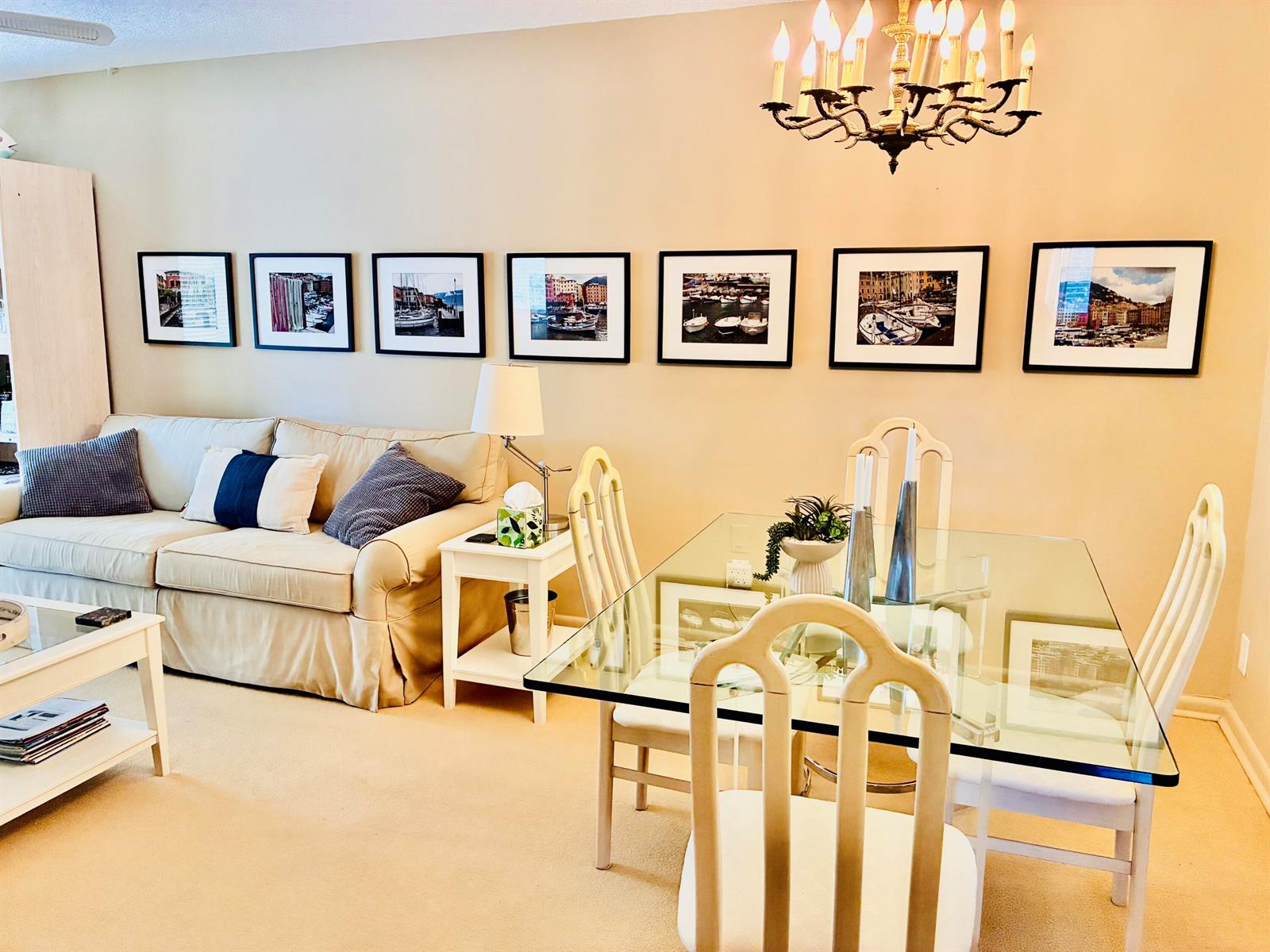 A dining area and living room feature a glass table, beige sofa, and wall-mounted photographs — 259 S Cypress Road # 533, Pompano Beach FL 33060, POMPANO BEACH, FL