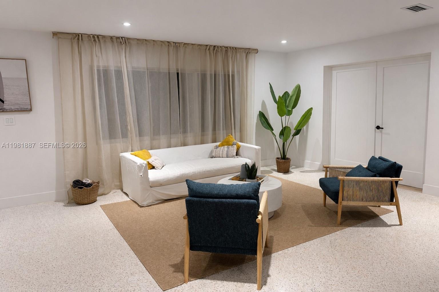 A living room features a white sofa, two blue armchairs, and a large potted plant — 1240 Binney Dr, Fort Pierce FL 34949, FORT PIERCE, FL
