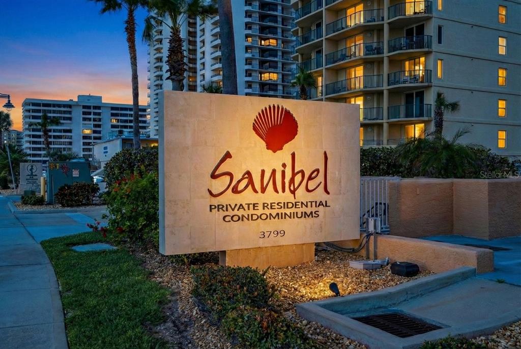 A stone sign for the Sanibel Private Residential Condominiums stands in front of tall buildings — 3799 S ATLANTIC AVENUE UNIT 601, DAYTONA BEACH SHORES, FL