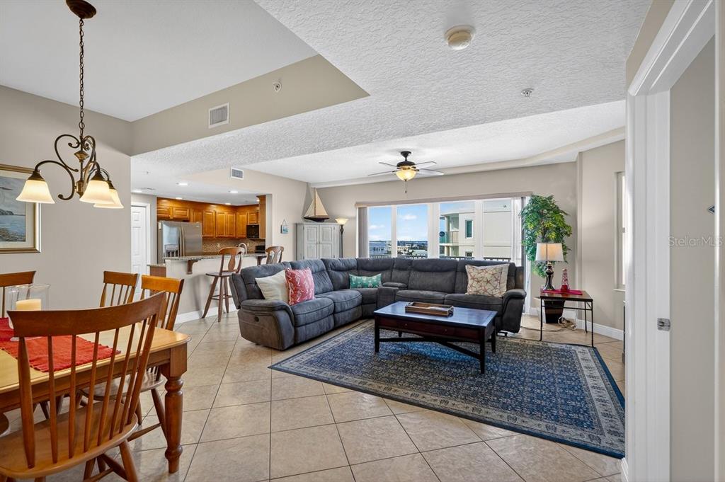 An open-concept living and dining area features tile flooring, a sectional sofa, and kitchen access — 3799 S ATLANTIC AVENUE UNIT 601, DAYTONA BEACH SHORES, FL
