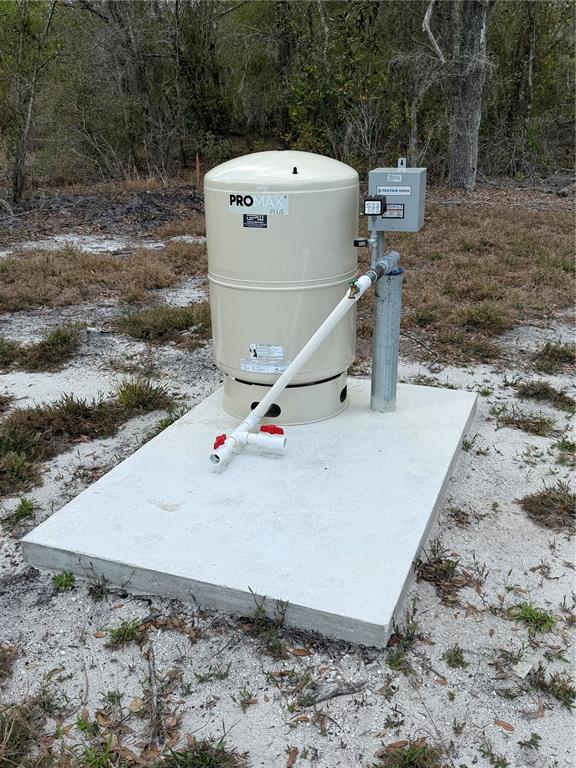 A beige well pressure tank sits on a concrete pad outdoors near a wooded area — 4021 BRUTON ROAD, PLANT CITY, FL