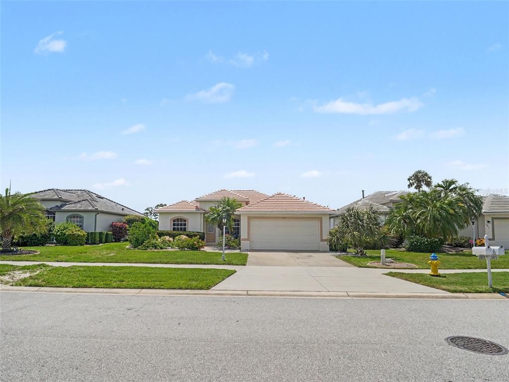 A single-story house with a tiled roof, garage, and front lawn under a blue sky — 2885 ROYAL PALM DRIVE, NORTH PORT, FL