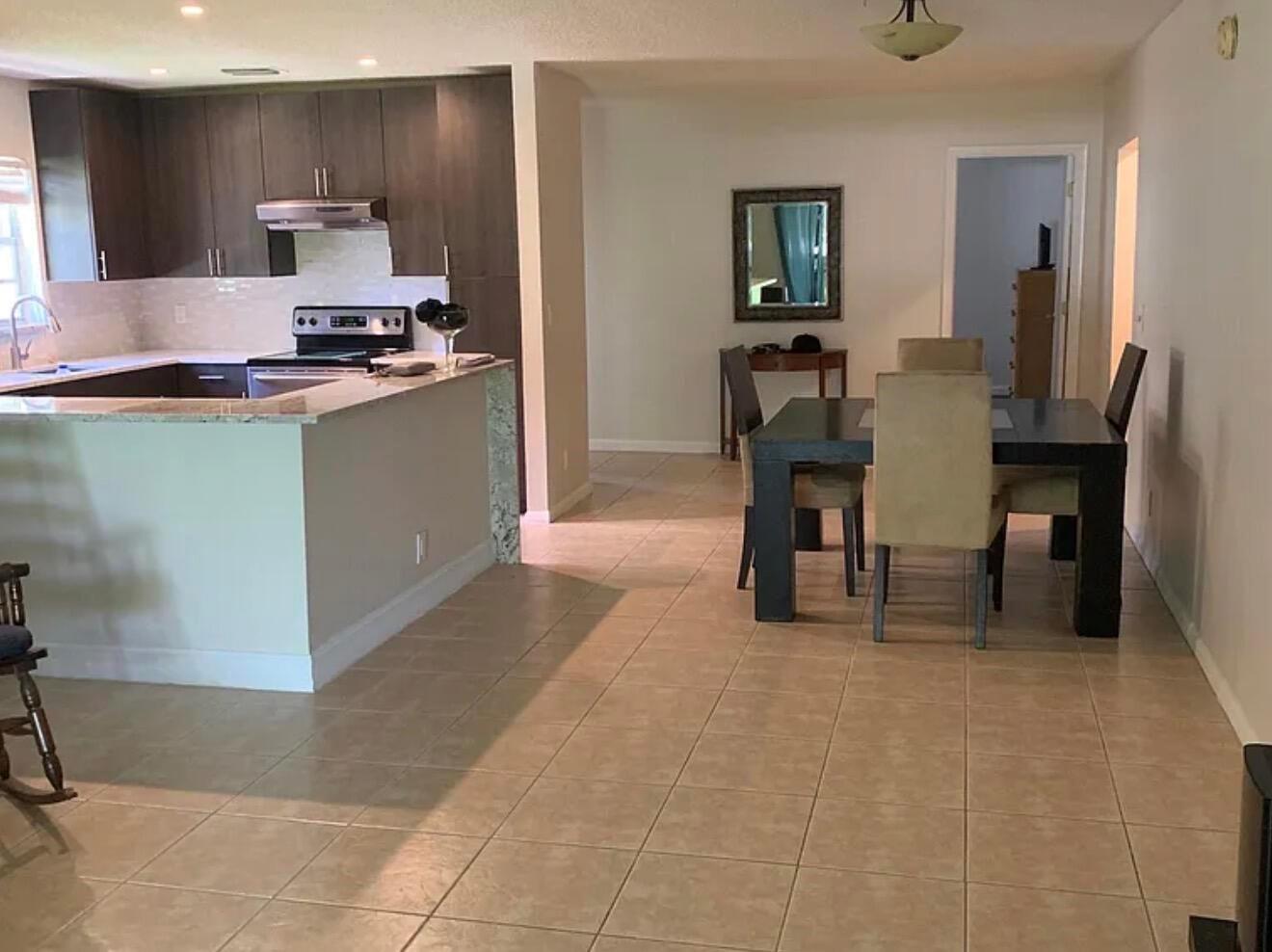 A kitchen with dark cabinets and a granite island opens into a tiled dining area — 22324 SW 57th Circle, Boca Raton FL 33428, BOCA RATON, FL