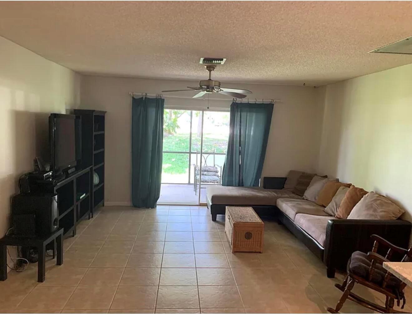 A living room with tile flooring, a sectional sofa, and a sliding glass door — 22324 SW 57th Circle, Boca Raton FL 33428, BOCA RATON, FL