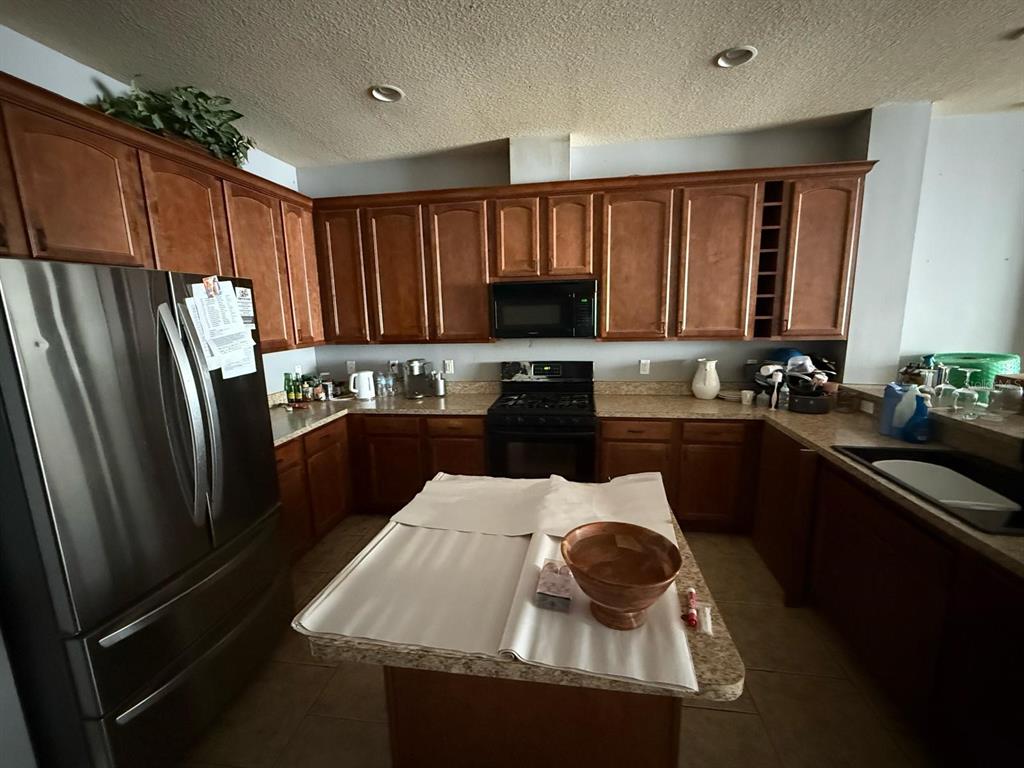 A kitchen features wood cabinets, stainless steel appliances, a center island, and tile flooring — 2101 VIA NAPOLI STREET, PLANT CITY, FL