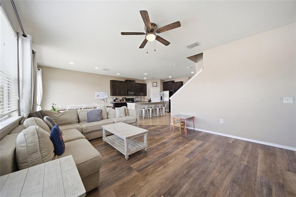 An open-concept living room and kitchen featuring wood-look flooring, a sectional sofa, and bar seating — 15476 STONE HOUSE DRIVE, BROOKSVILLE, FL