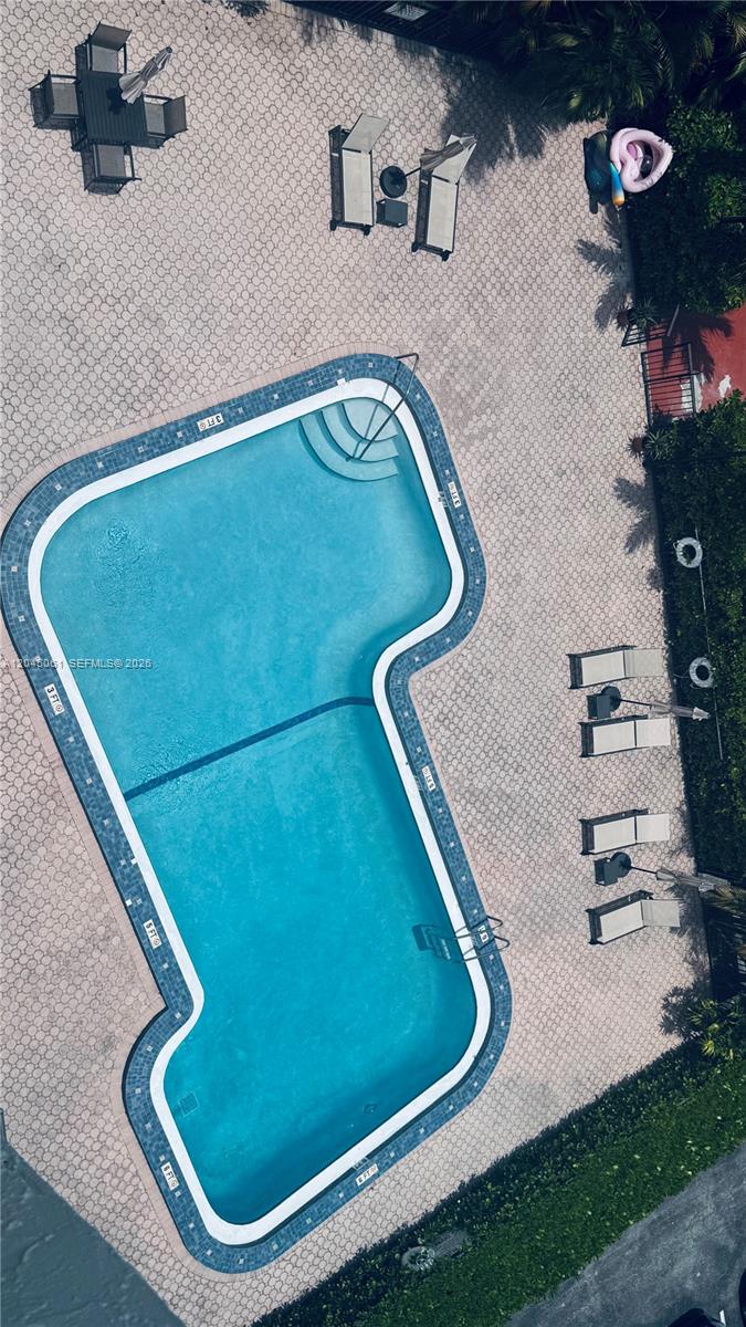 An aerial view shows an L-shaped swimming pool surrounded by a paved deck with lounge chairs — 1440 Brickell Bay Dr # 810, Miami FL 33131, MIAMI, FL