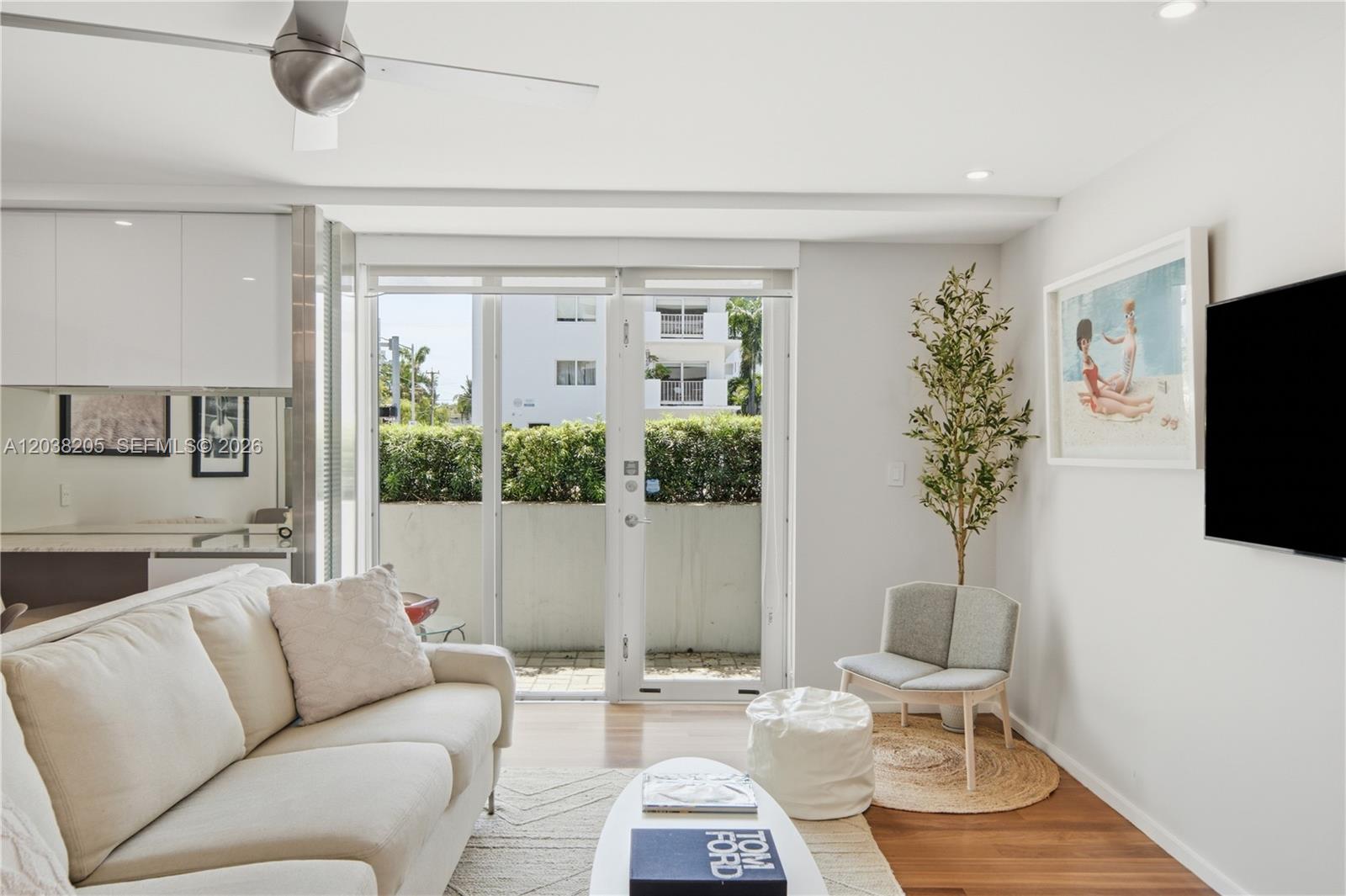 A living room features a white sofa, a coffee table, a chair, and glass patio doors — 1601 West Ave # 101, Miami Beach FL 33139, MIAMI BEACH, FL