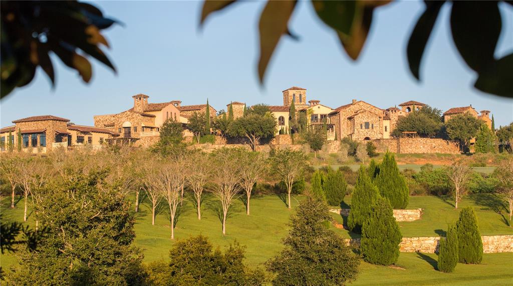 A large stone estate sits on a grassy hill surrounded by trees and landscaping — 16401 PENDIO DRIVE, BELLA COLLINA, FL