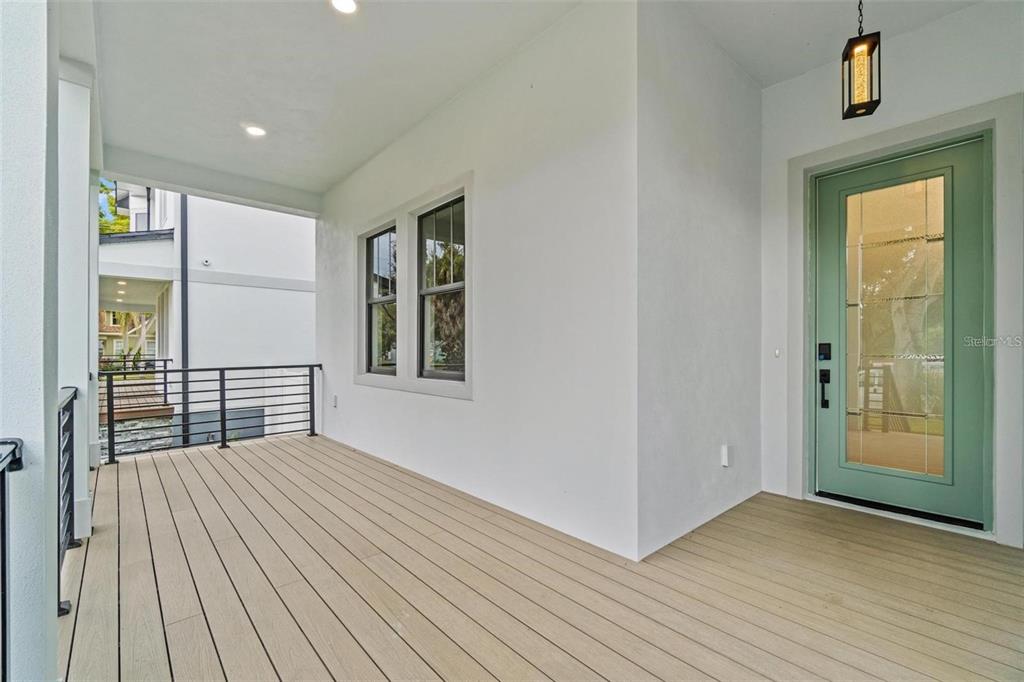 A covered porch features light-colored composite decking, white walls, and a sage green front door — 403 PARK BLVD, OLDSMAR, FL