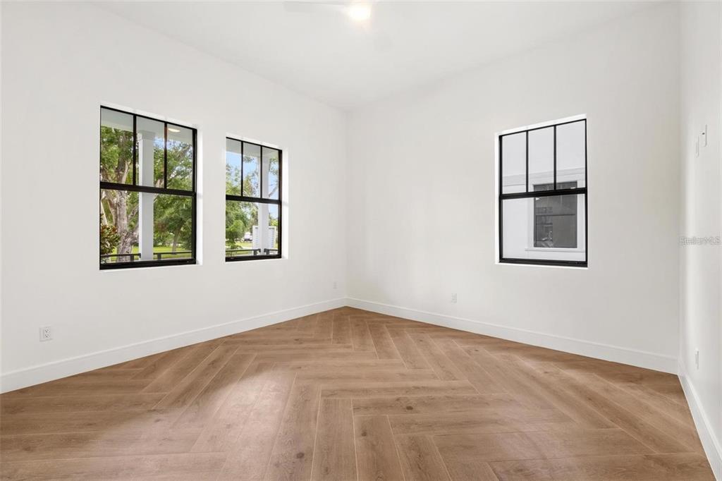 An empty room with white walls, herringbone wood flooring, and black-framed windows — 403 PARK BLVD, OLDSMAR, FL