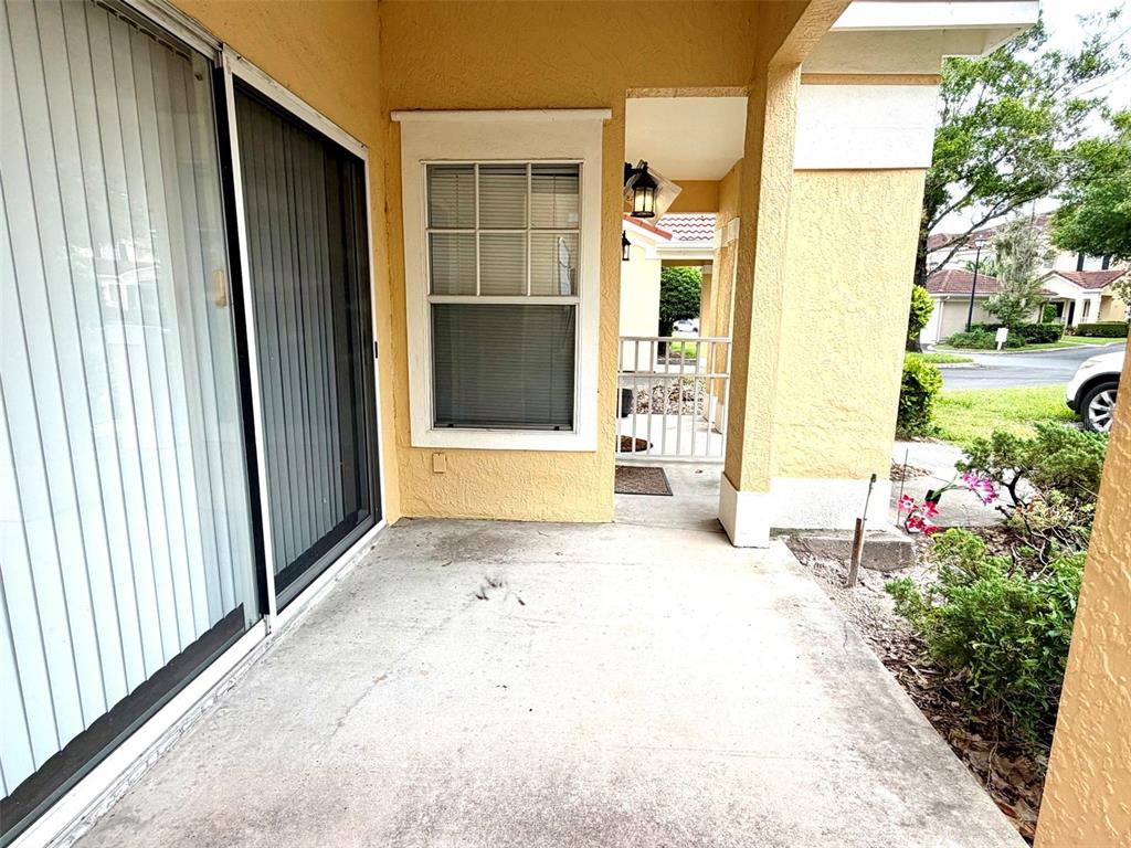 A concrete patio features a sliding glass door, a single window, and a covered entryway — 413 ARBOR LAKES CIRCLE UNIT 413, SANFORD, FL