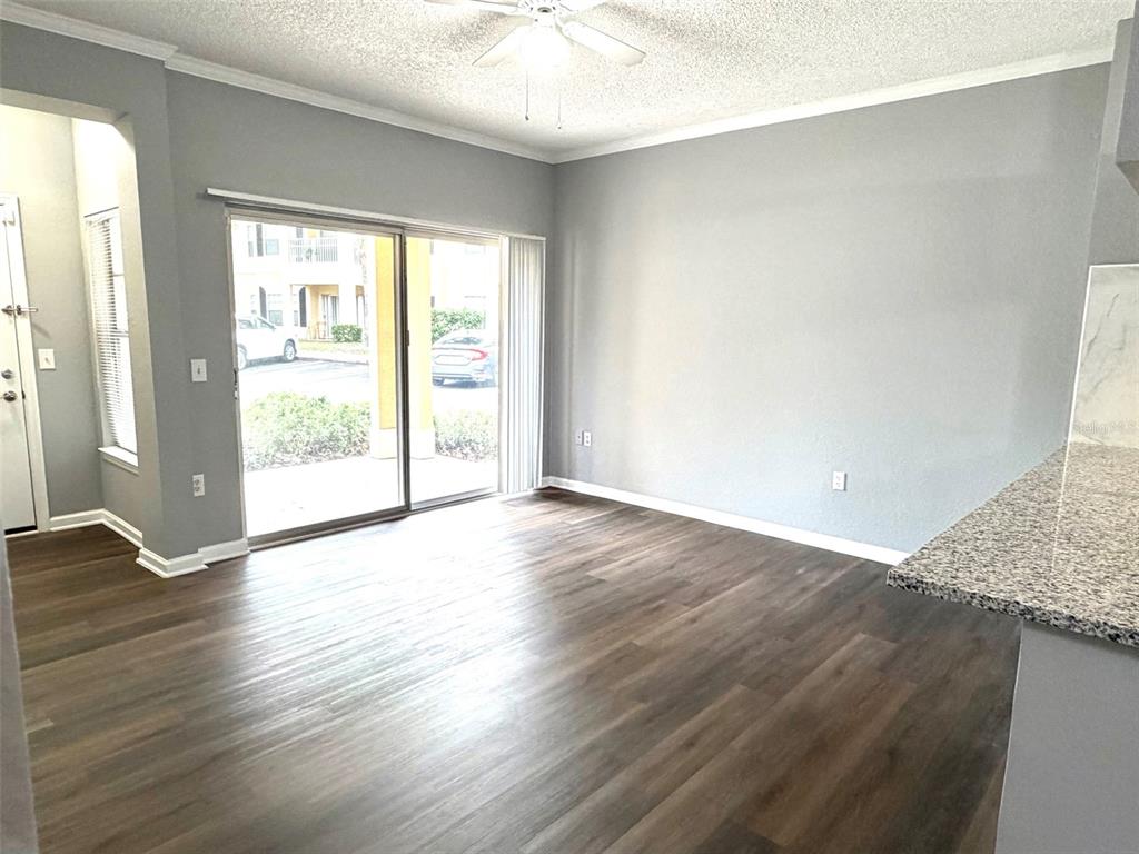 An empty living room features gray walls, wood-look flooring, a ceiling fan, and sliding glass doors — 413 ARBOR LAKES CIRCLE UNIT 413, SANFORD, FL