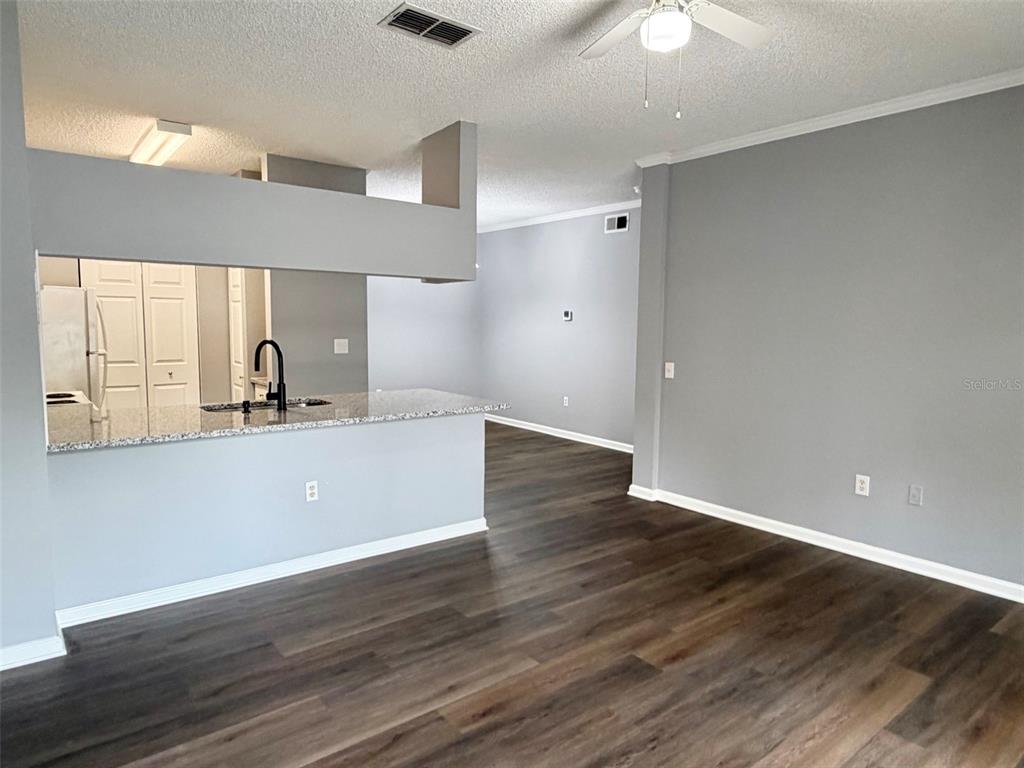 An open-concept living area features gray walls, dark wood-look flooring, and a kitchen breakfast bar — 413 ARBOR LAKES CIRCLE UNIT 413, SANFORD, FL