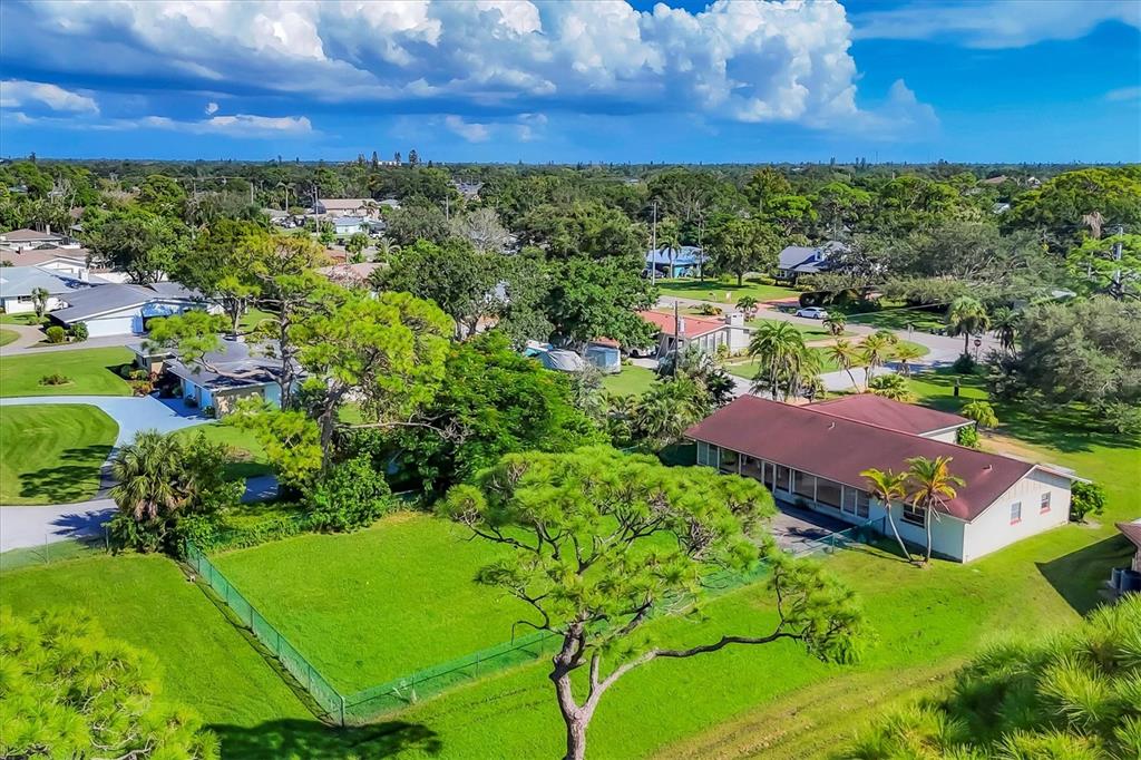 An aerial view shows a residential neighborhood with a fenced yard and a house — 4704 18TH AVENUE W, BRADENTON, FL
