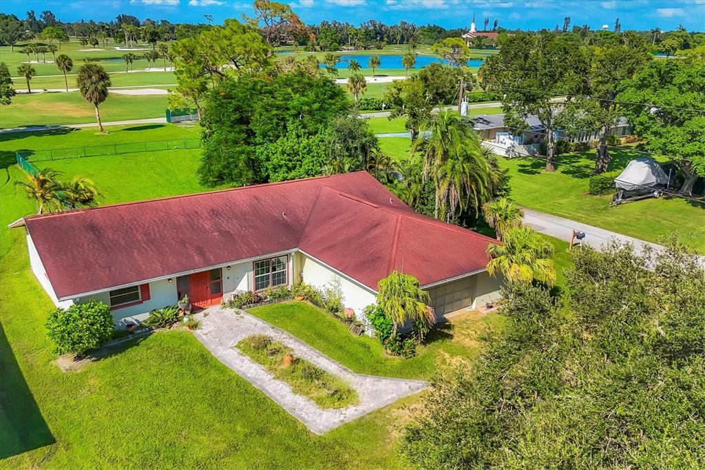 An aerial view of a single-story house with a red roof and a golf course — 4704 18TH AVENUE W, BRADENTON, FL