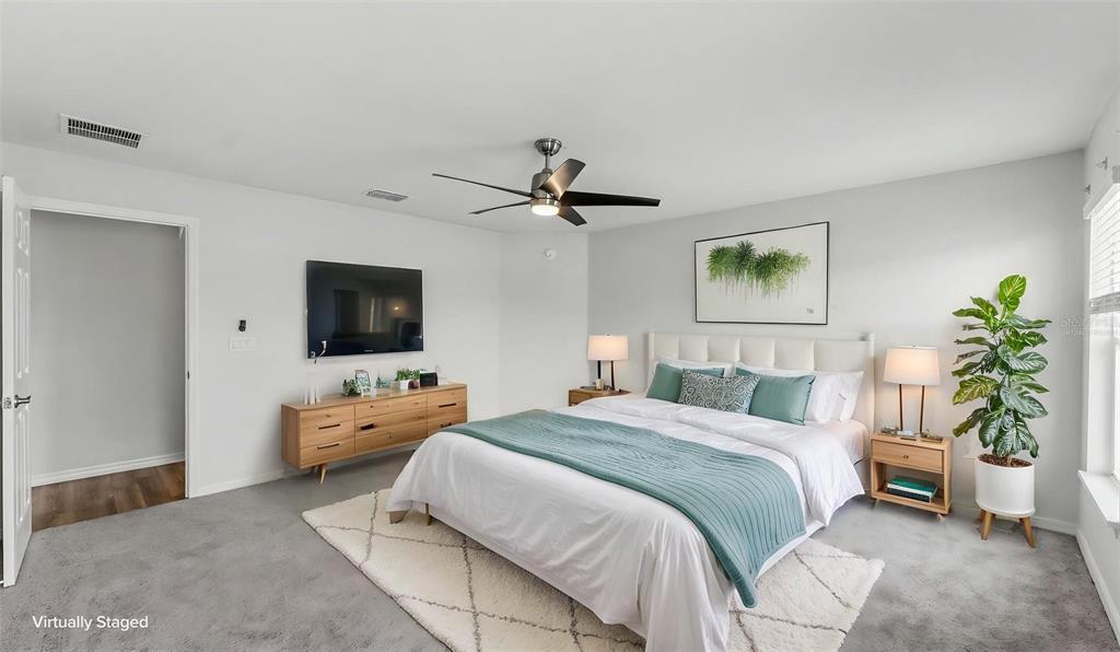 A virtually staged bedroom features a bed, dresser, ceiling fan, and a potted plant — 2638 SAN MARCO WAY, WINTER HAVEN, FL