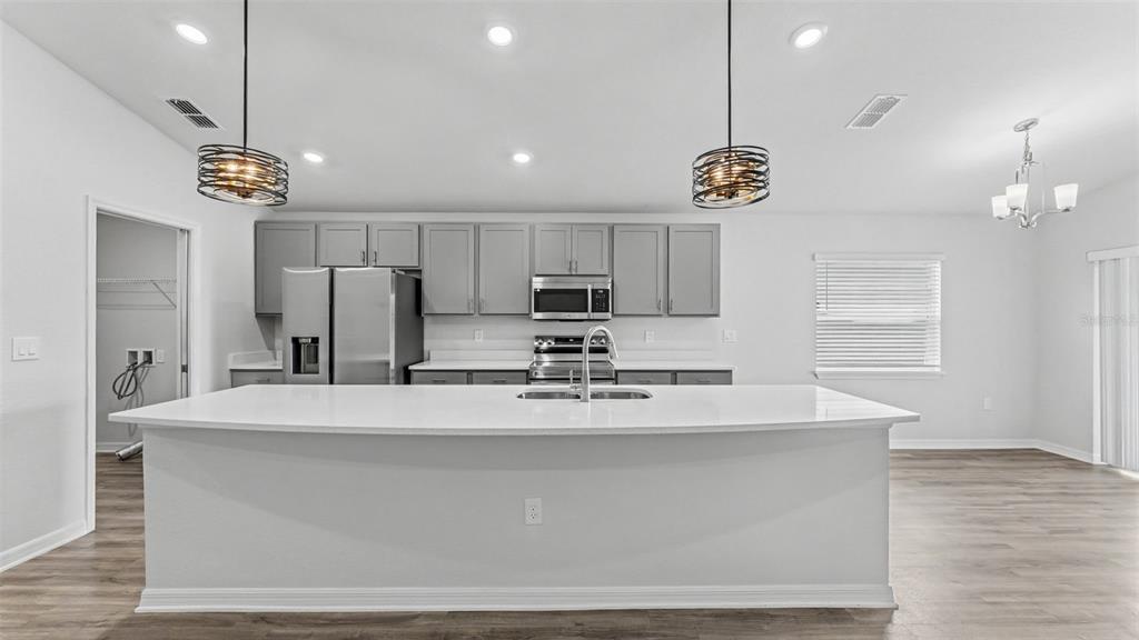 A modern kitchen features a large white island, gray cabinetry, and stainless steel appliances — 2638 SAN MARCO WAY, WINTER HAVEN, FL