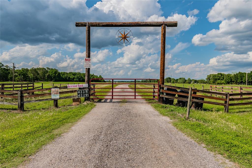 A gravel driveway leads to a red metal gate at the entrance of a ranch — 6225, 6229 DEEN STILL ROAD, LAKELAND, FL