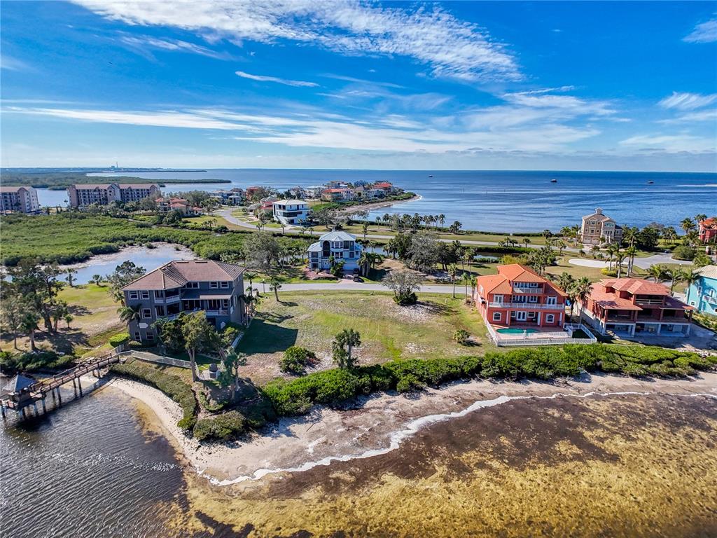 An aerial view shows several waterfront homes along a coastline with a wooden pier — Lot 46 HARBORPOINTE DR., PORT RICHEY, FL