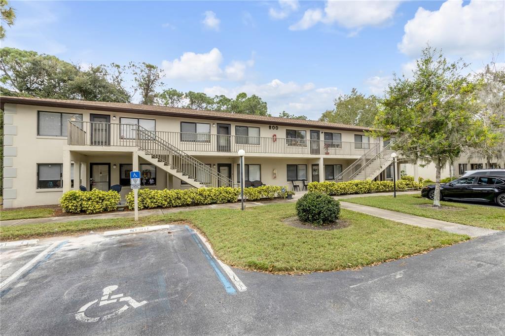 A two-story apartment building with exterior staircases, a parking lot, and a handicap space — 1601 BIG TREE ROAD UNIT 807, SOUTH DAYTONA, FL