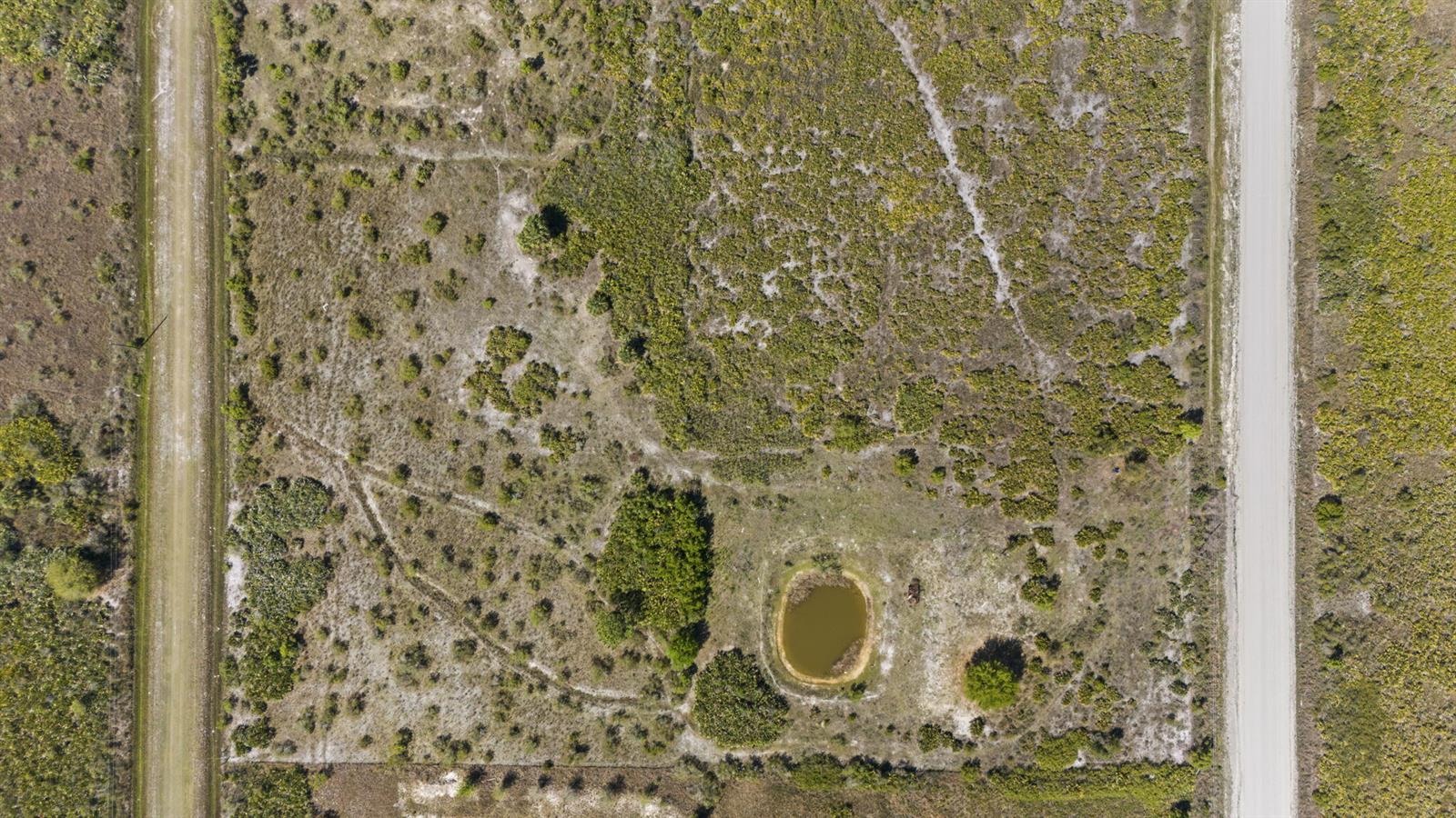 An aerial view shows a rectangular plot of land with a small pond and vegetation — 19050 NW 256th Street, Okeechobee FL 34972, OKEECHOBEE, FL