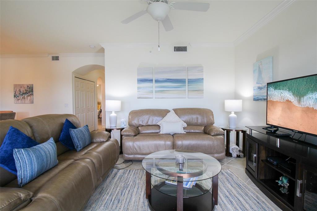 A living room features two brown leather sofas, a glass coffee table, and a television — 16814 VARDON TERRACE UNIT 102, BRADENTON, FL