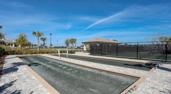 An outdoor shuffleboard court sits next to a fenced tennis court under a blue sky — 16814 VARDON TERRACE UNIT 102, BRADENTON, FL