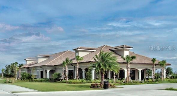 A low-angle exterior view of a beige clubhouse with a tiled roof and palm trees — 16814 VARDON TERRACE UNIT 102, BRADENTON, FL
