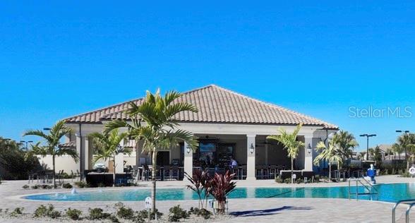 A swimming pool sits in front of a covered outdoor bar area with palm trees — 16814 VARDON TERRACE UNIT 102, BRADENTON, FL