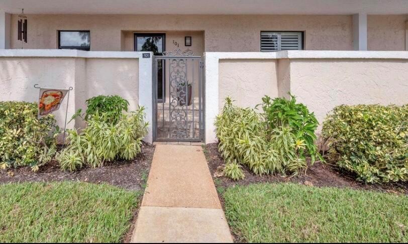 A concrete walkway leads to a gated entryway of a beige stucco residential building — 300 N Hwy A1a # 101h, Jupiter FL 33477, JUPITER, FL
