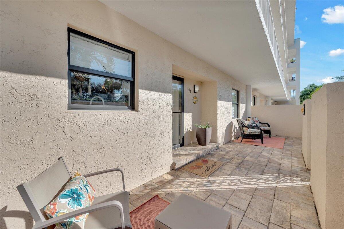 A paved outdoor patio features a front door, seating, and a window on a stucco wall — 300 N Hwy A1a # 101h, Jupiter FL 33477, JUPITER, FL