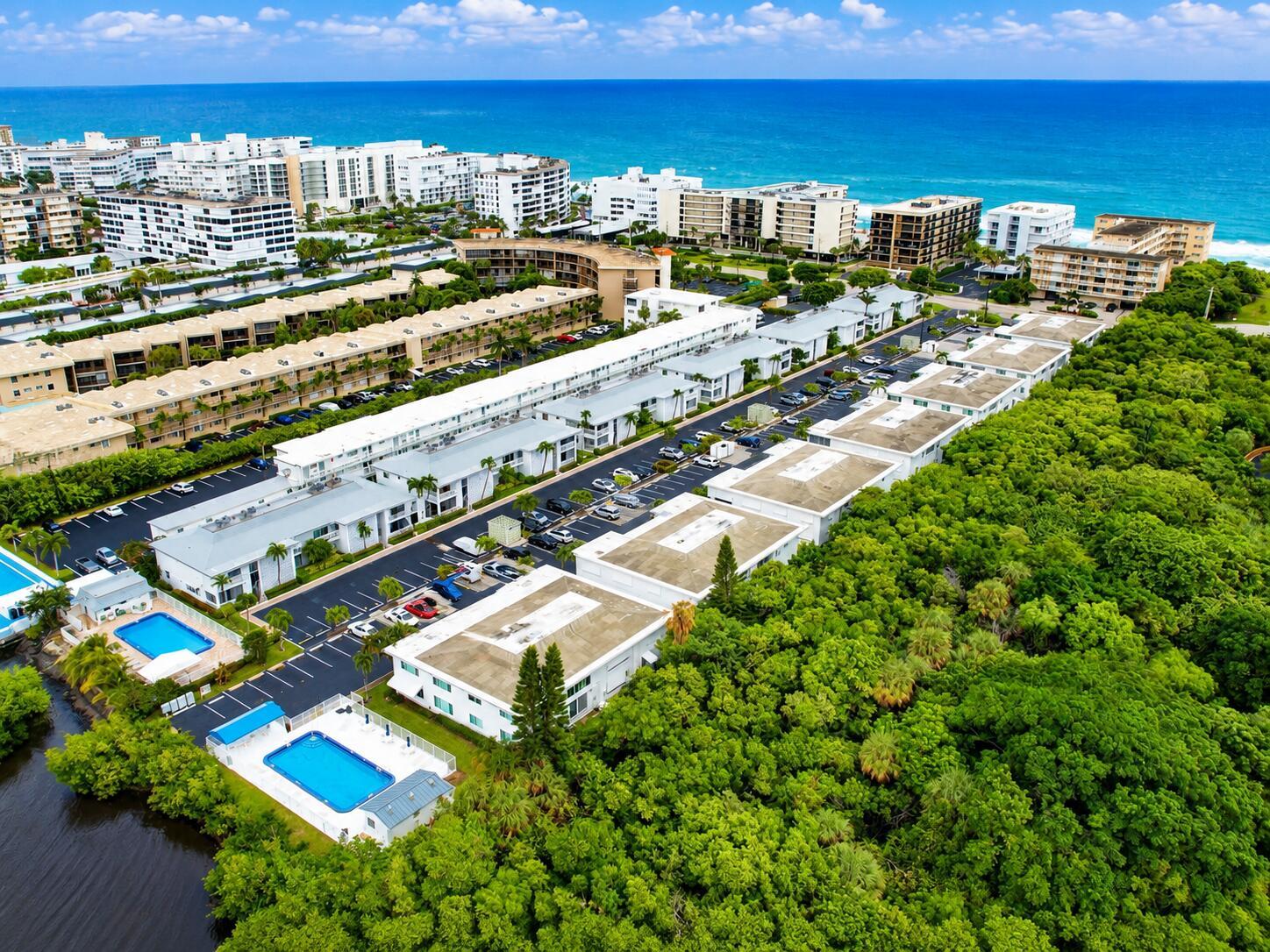 An aerial view shows a residential complex with multiple swimming pools and surrounding lush trees — 4501 S Ocean Boulevard # D4, South Palm Beach FL 33480, SOUTH PALM BEACH, FL