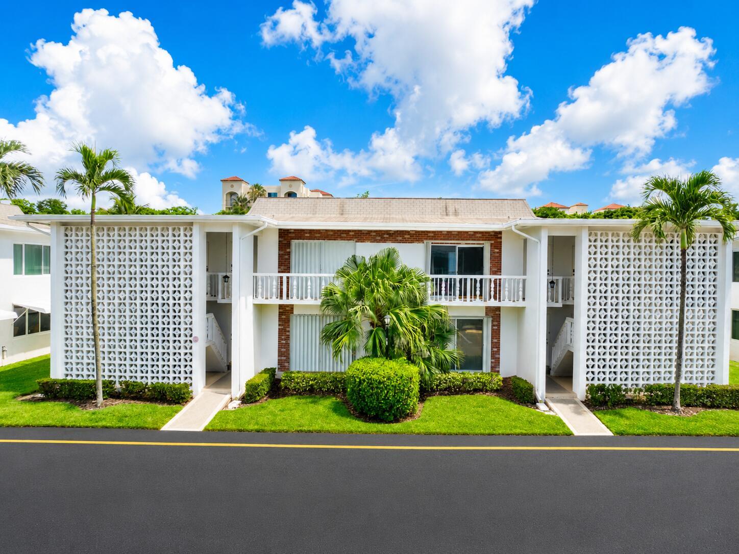 A two-story apartment building features white breeze block walls, a brick facade, and palm trees — 4501 S Ocean Boulevard # D4, South Palm Beach FL 33480, SOUTH PALM BEACH, FL