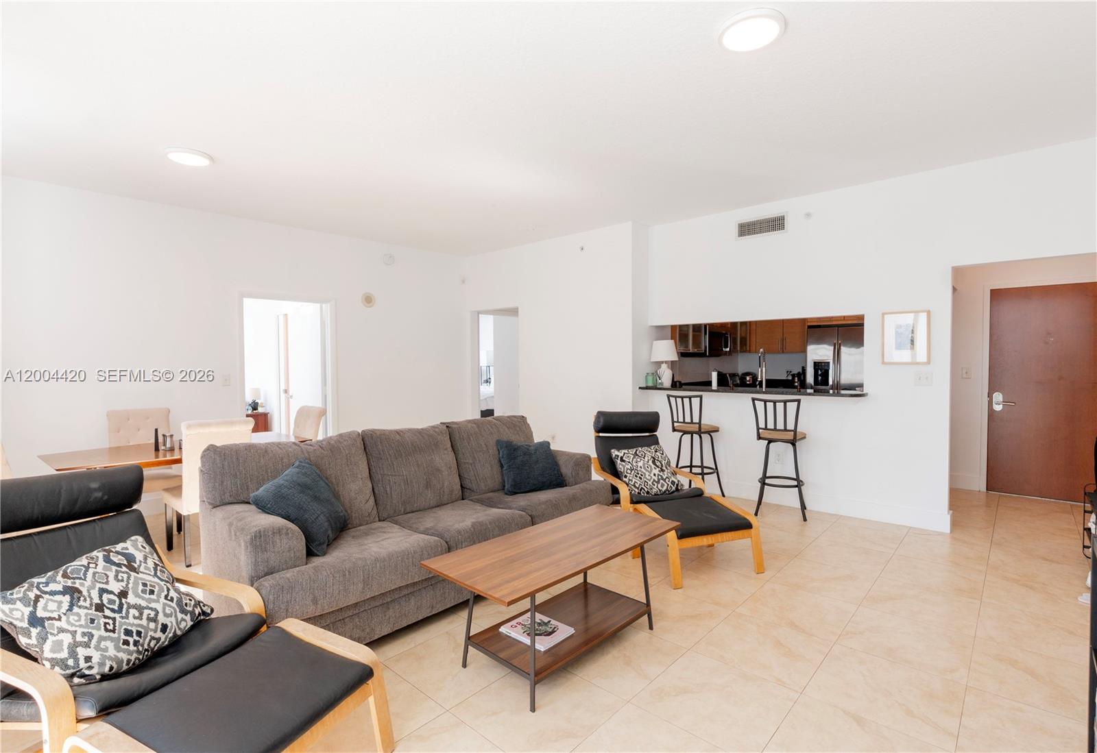 A living room features a gray sofa, two black lounge chairs, and a kitchen pass-through — 31 SE 5th St # 4121, Miami FL 33131, MIAMI, FL