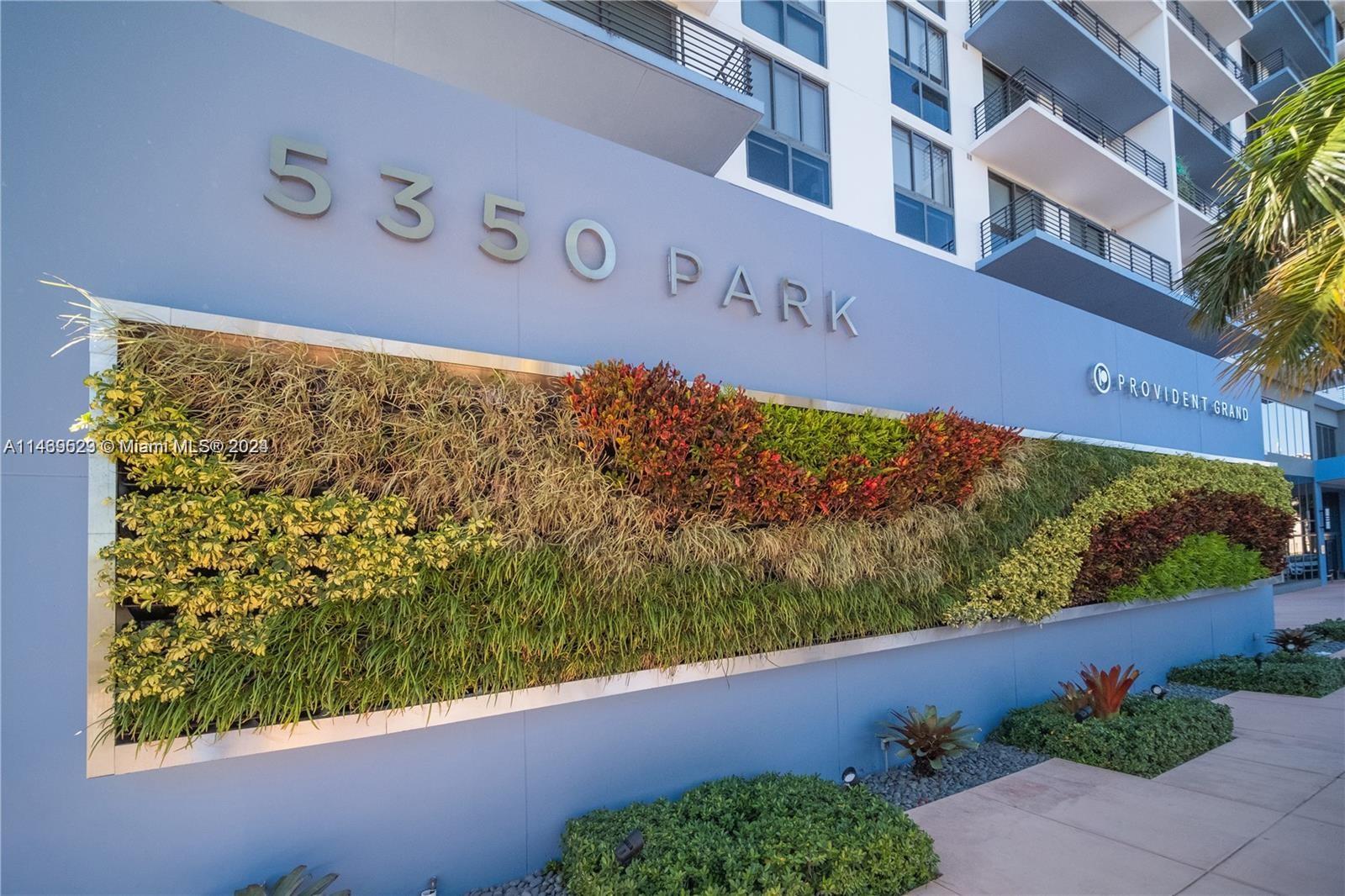 The exterior of a building features a large vertical garden wall and metal signage — 5350 NW 84th Ave # 1514, Doral FL 33166, DORAL, FL